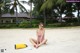 A woman in a pink bathing suit sitting on the beach.