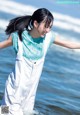 A young girl standing in the ocean with her arms outstretched.