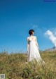 A woman in a white dress standing in tall grass.