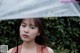 A woman holding an umbrella in front of a bush.