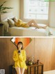 A woman in a yellow sweater is sitting on a bed.