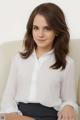 A woman sitting on a white couch wearing a white shirt.