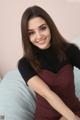 A woman sitting on a bed smiling at the camera.