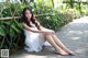 A woman in a white dress sitting on a brick walkway.